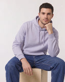 Mann im lilafarbenen Hoodie sitzt auf einem Holzhocker