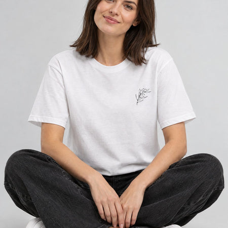 Frau sitzt im weißen Olivetree-Shirt