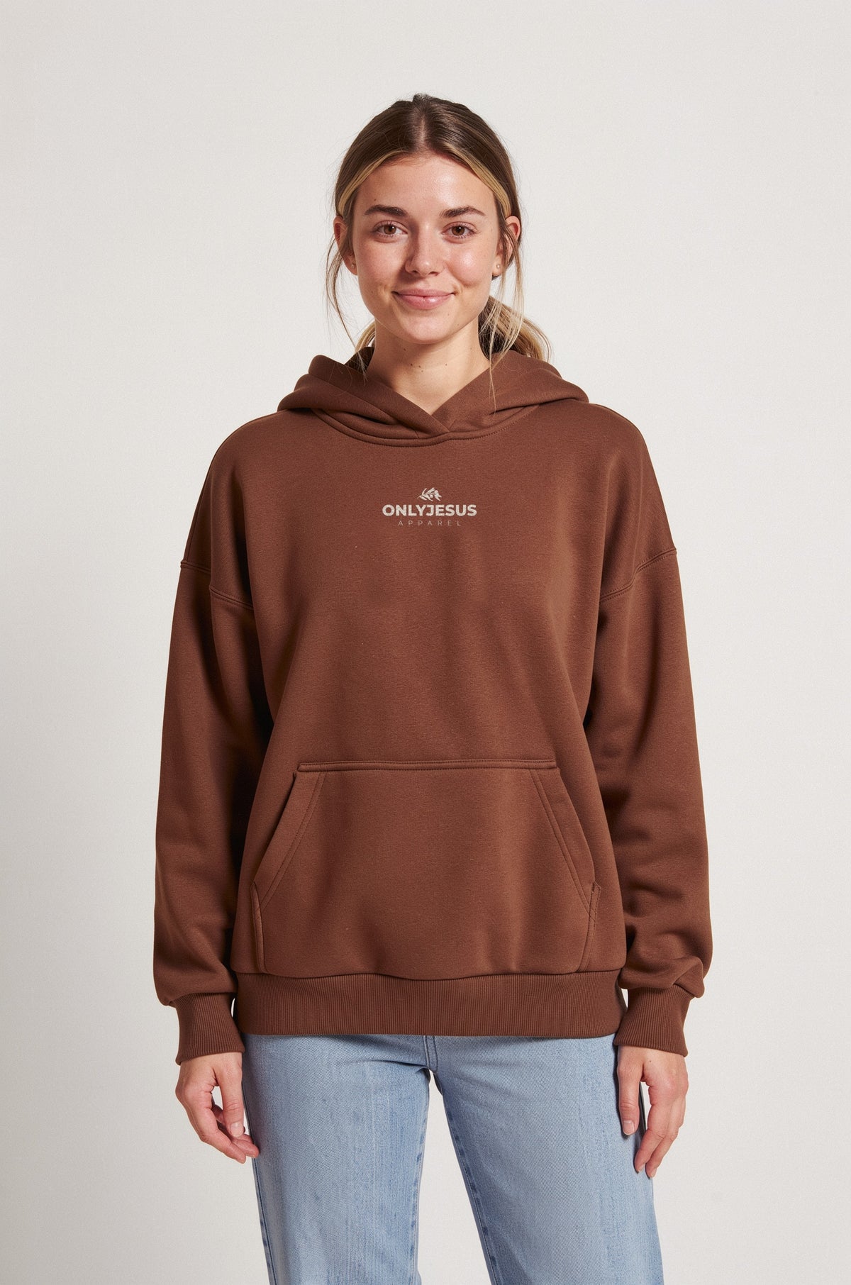 Frau im braunen OnlyJesus Fluffy Hoodie, Vorderseite mit kleinem Logo und Olivenzweig auf der Brust