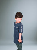 Junge im blauen Father's House Kindershirt von der Seite