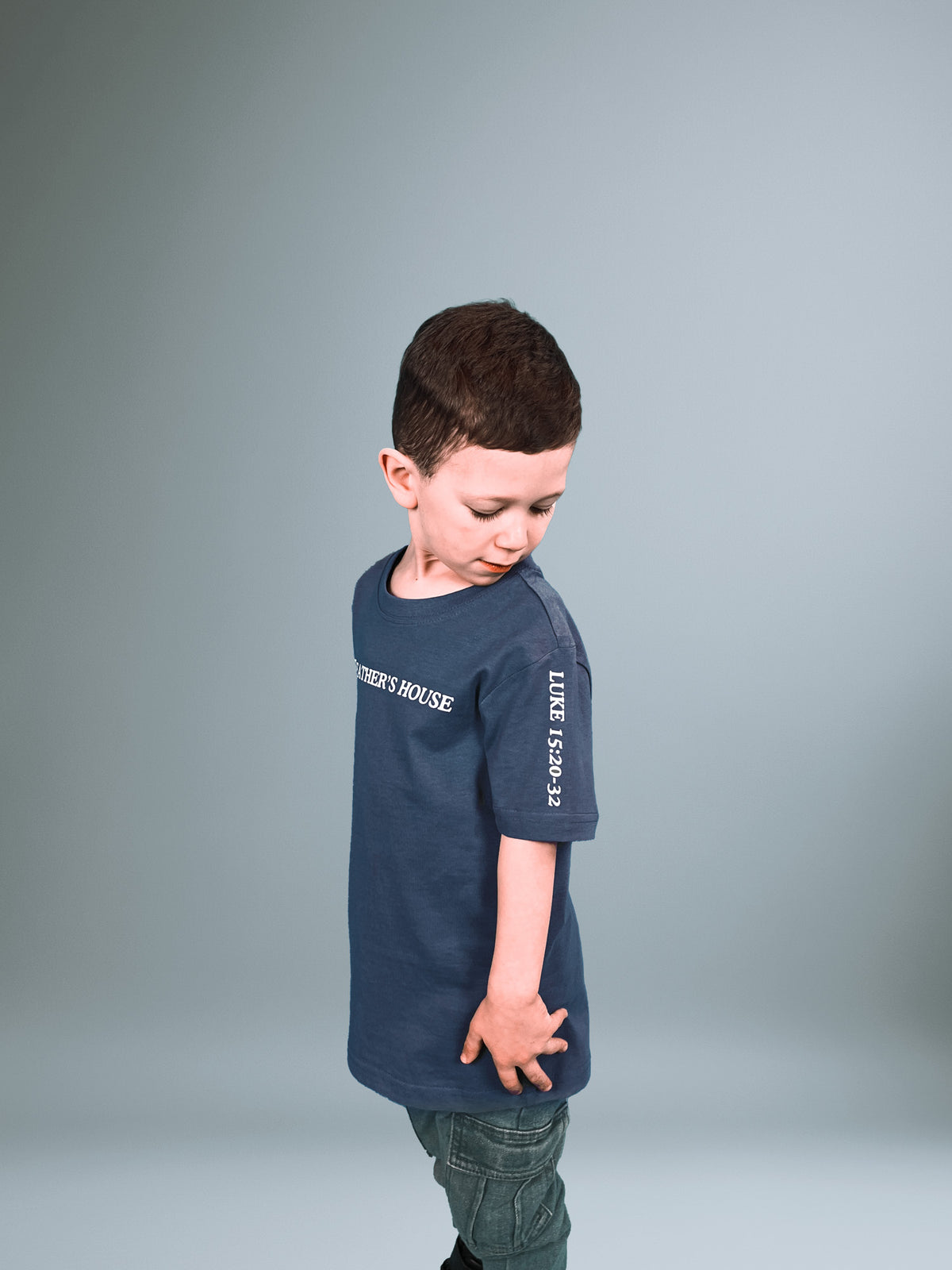 Junge im blauen Father's House Kindershirt von der Seite