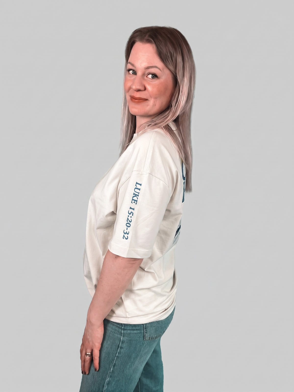 Frau im hellen Father's House Shirt von der Seite, Lukas 15,20-32 auf dem Ärmel