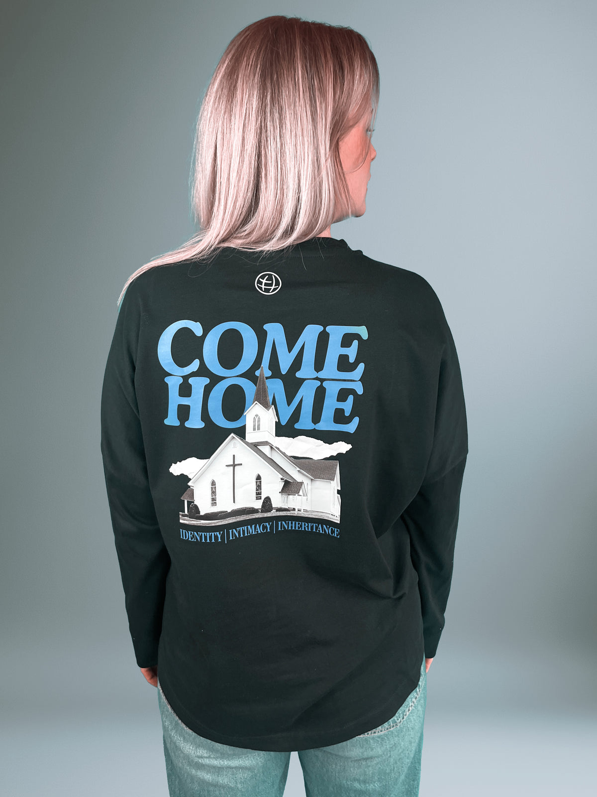 Frau von hinten im schwarzen Father's House Longsleeve mit Come Home Kirchenmotiv